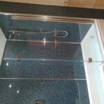 A shower with glass doors and a tiled floor.